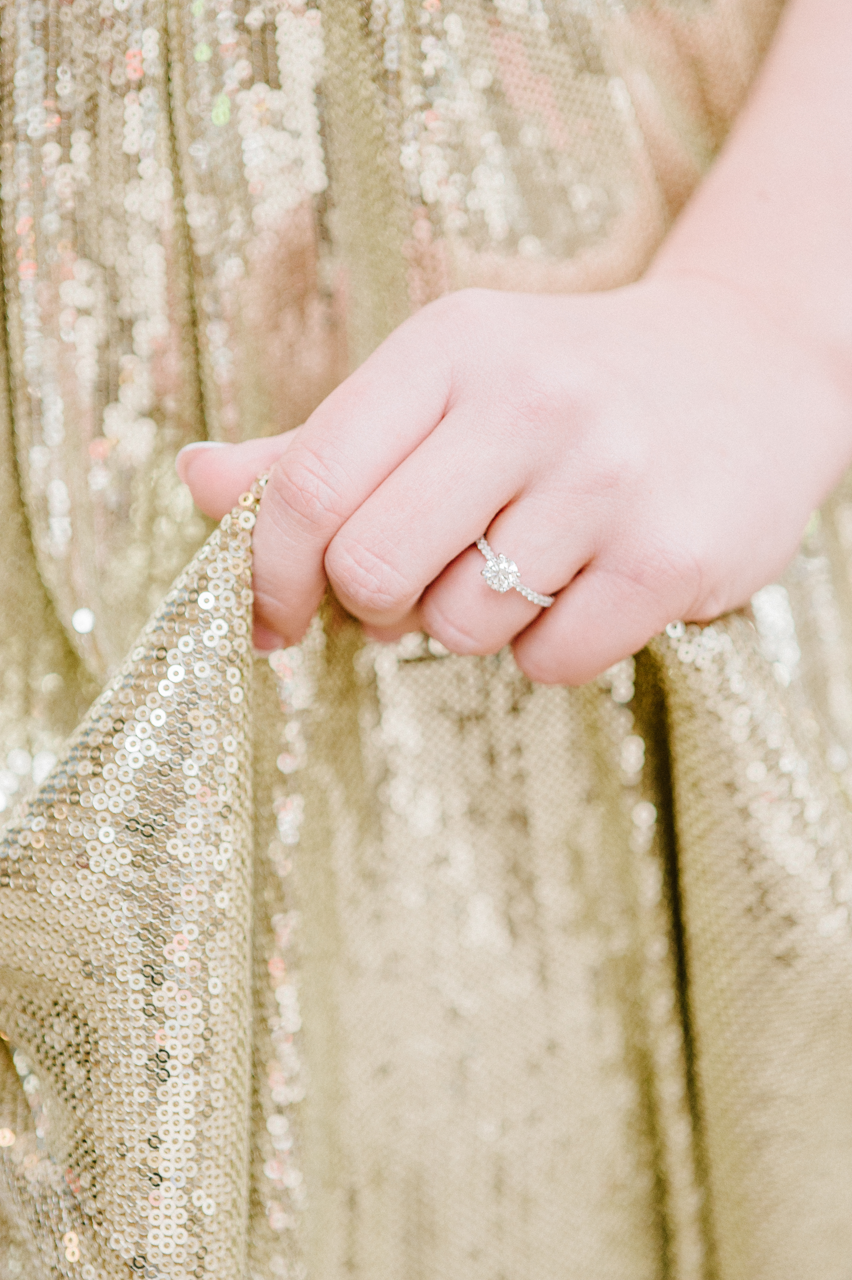 girl with engagement ring holding gold badgley mischka dress