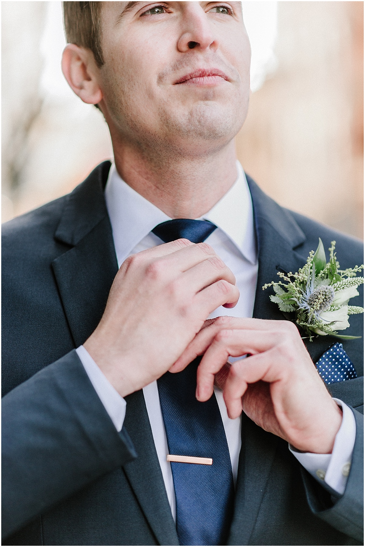 groom in blue suit fixing blue tie