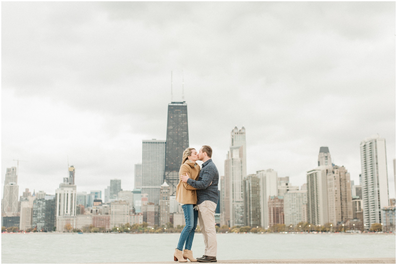 couple standing on ledge in front of lake and skyline