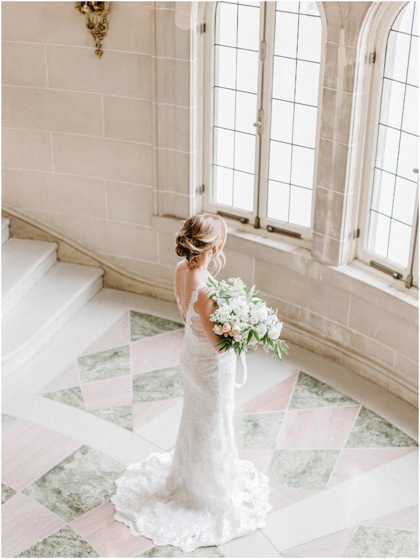 bride holding bouquet looking out a wall of windows