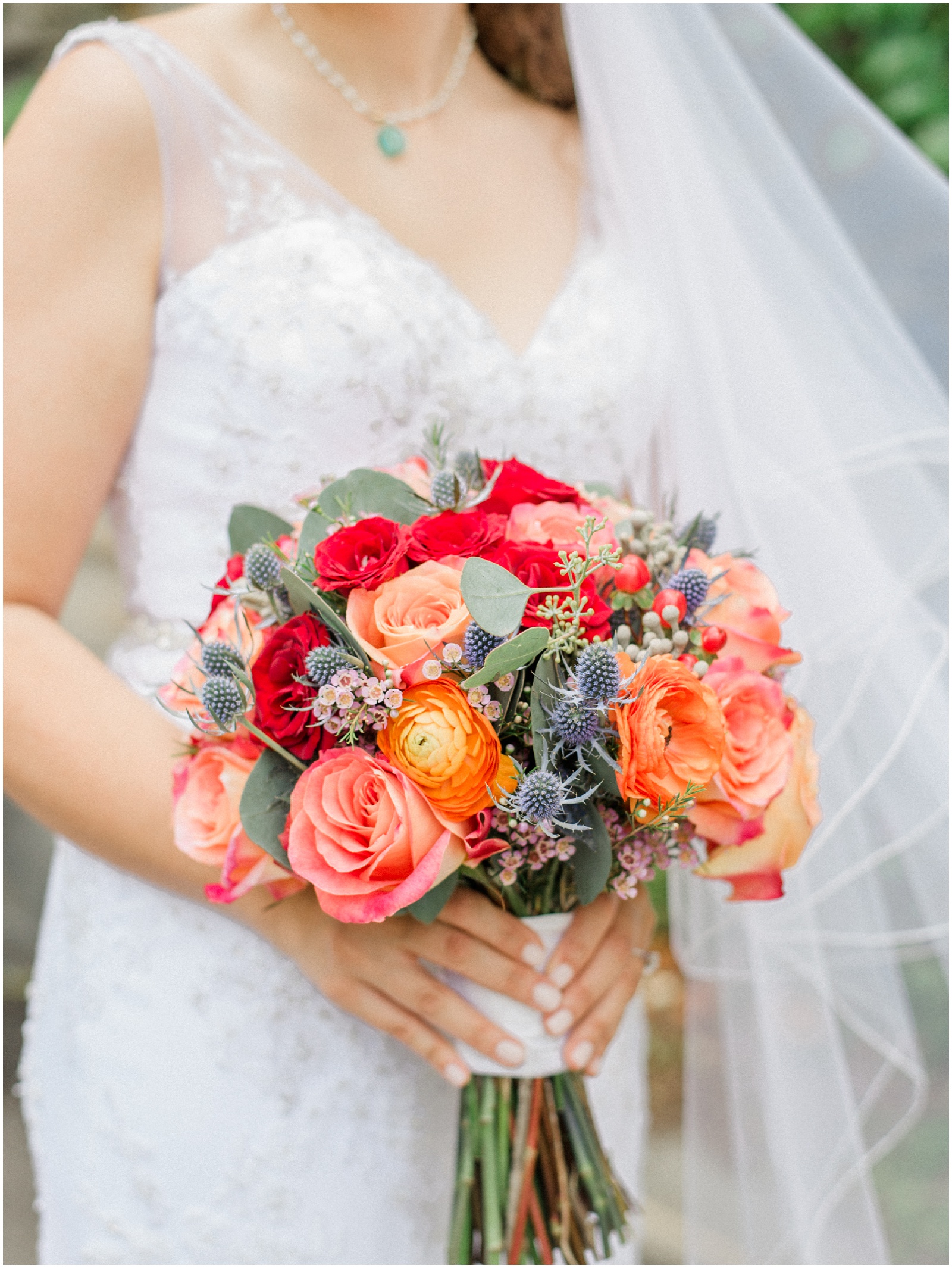 bride holding orange pink red wedding bouquet