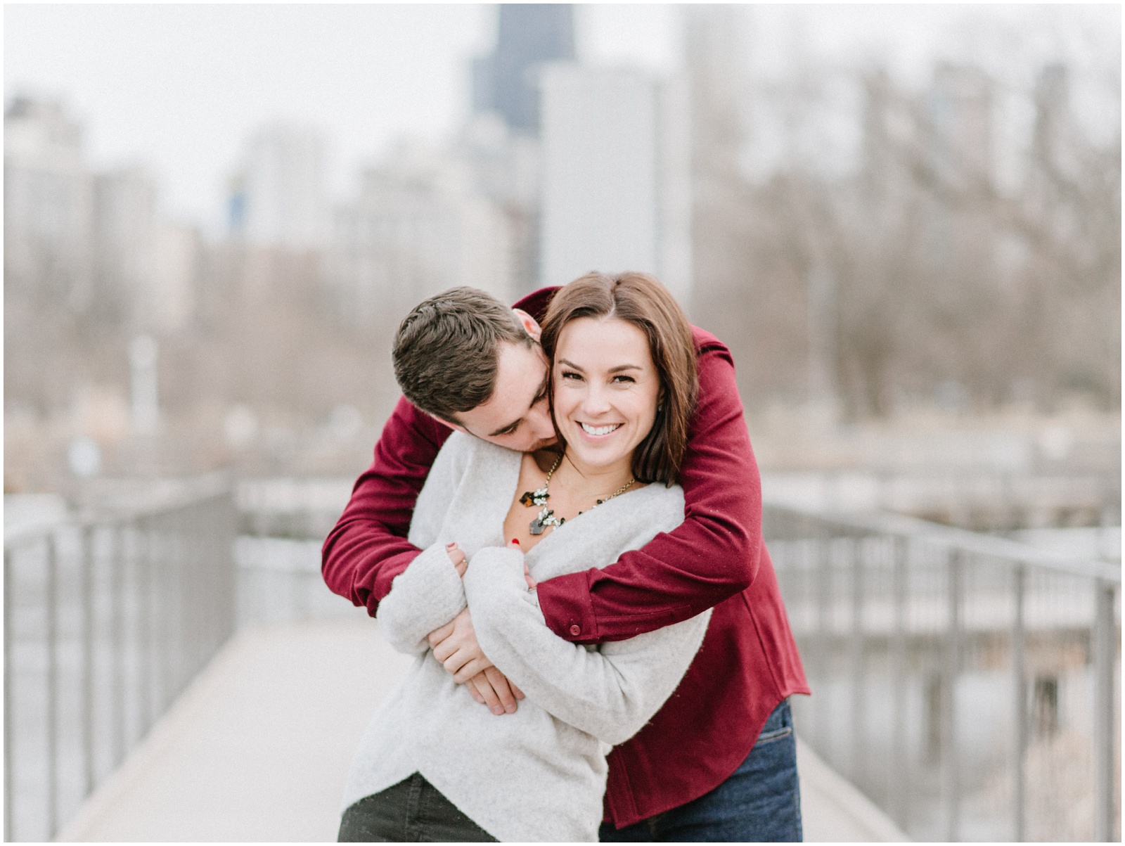 couple cuddling in front of chicago skyline for engagement photos