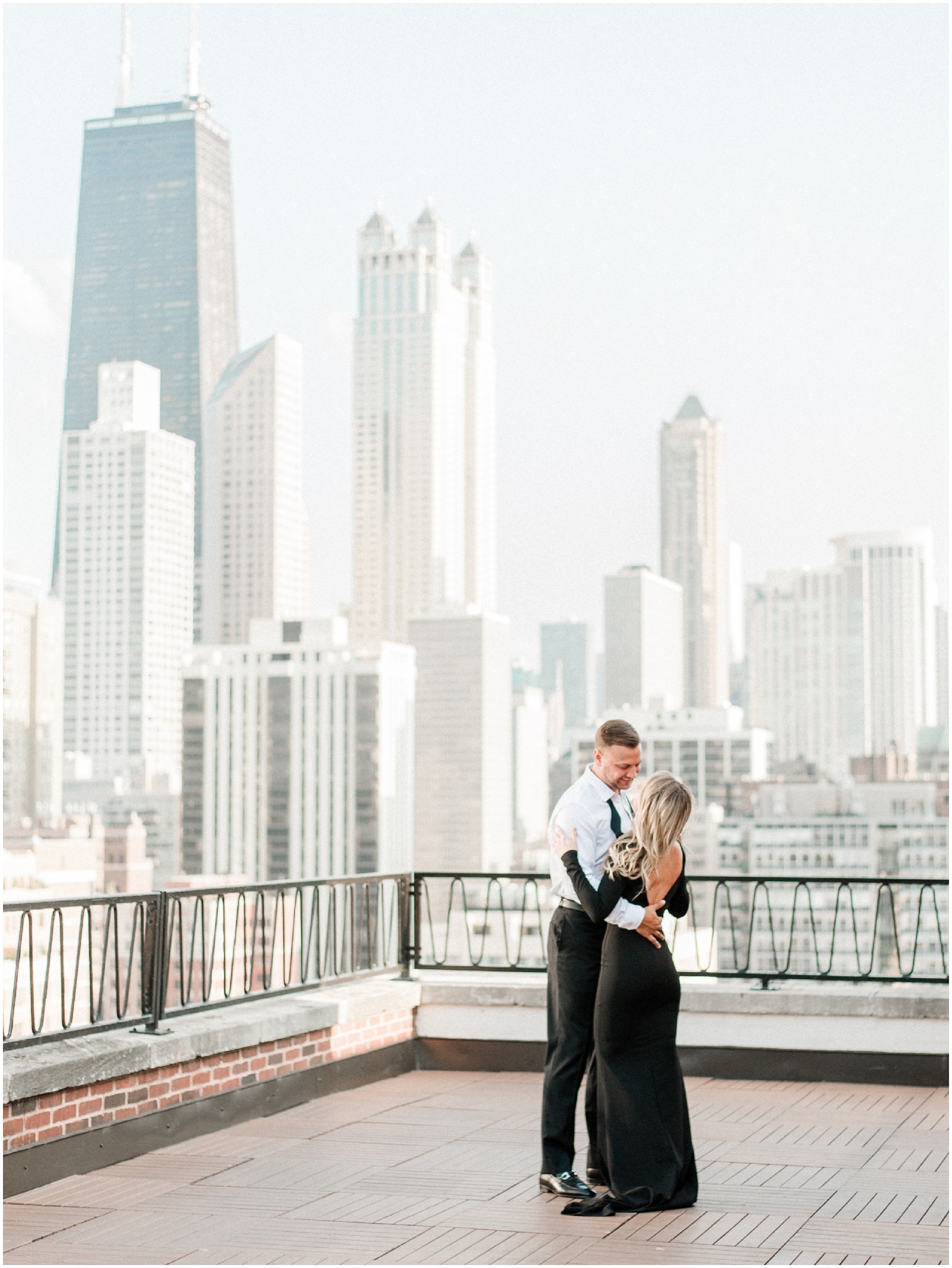couple wearing elegant black and white dancing on a rooftop in downtown chicago for engagement session