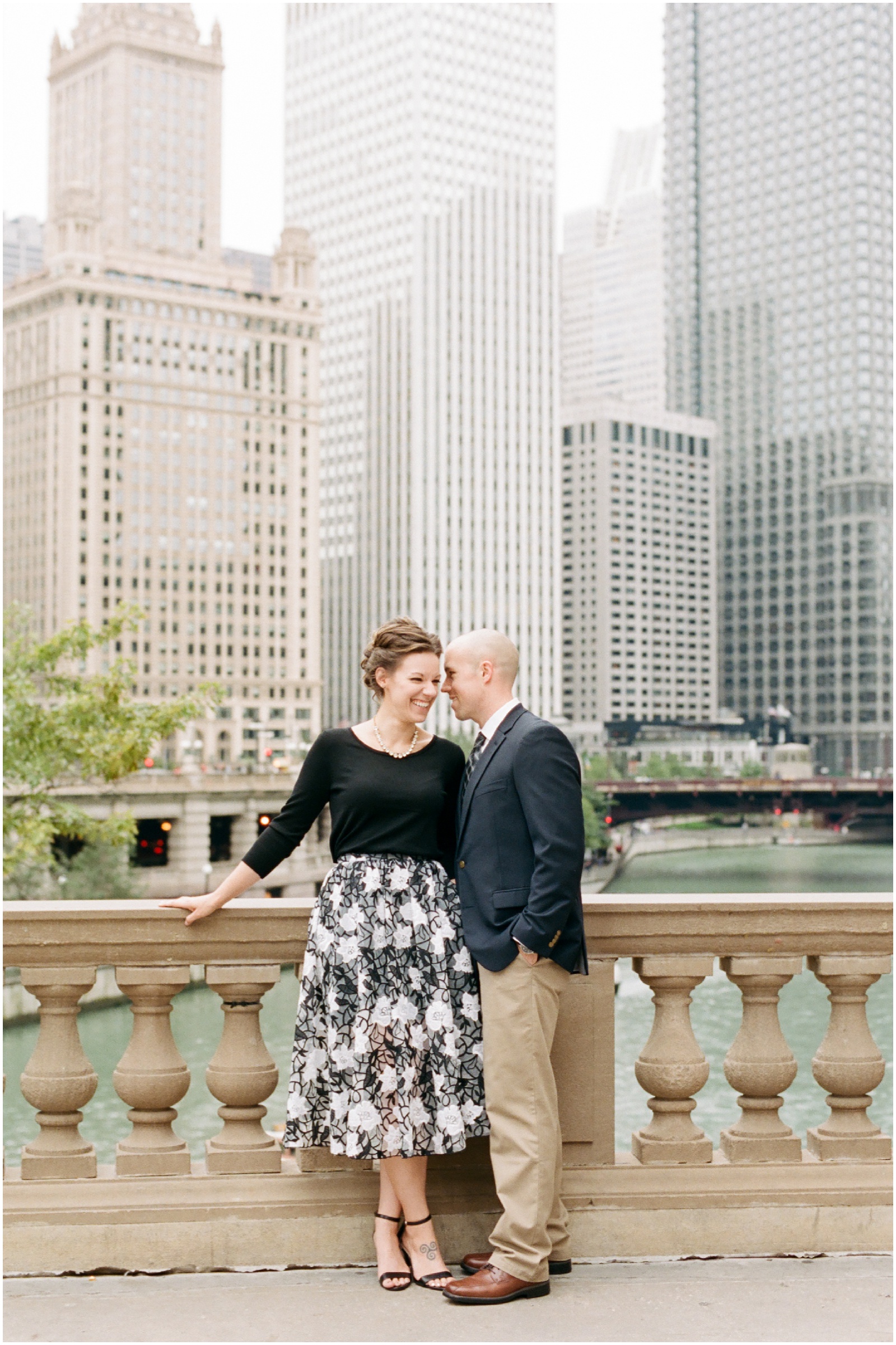 couple standing next to rail overlooking downtown chicago for engagement session