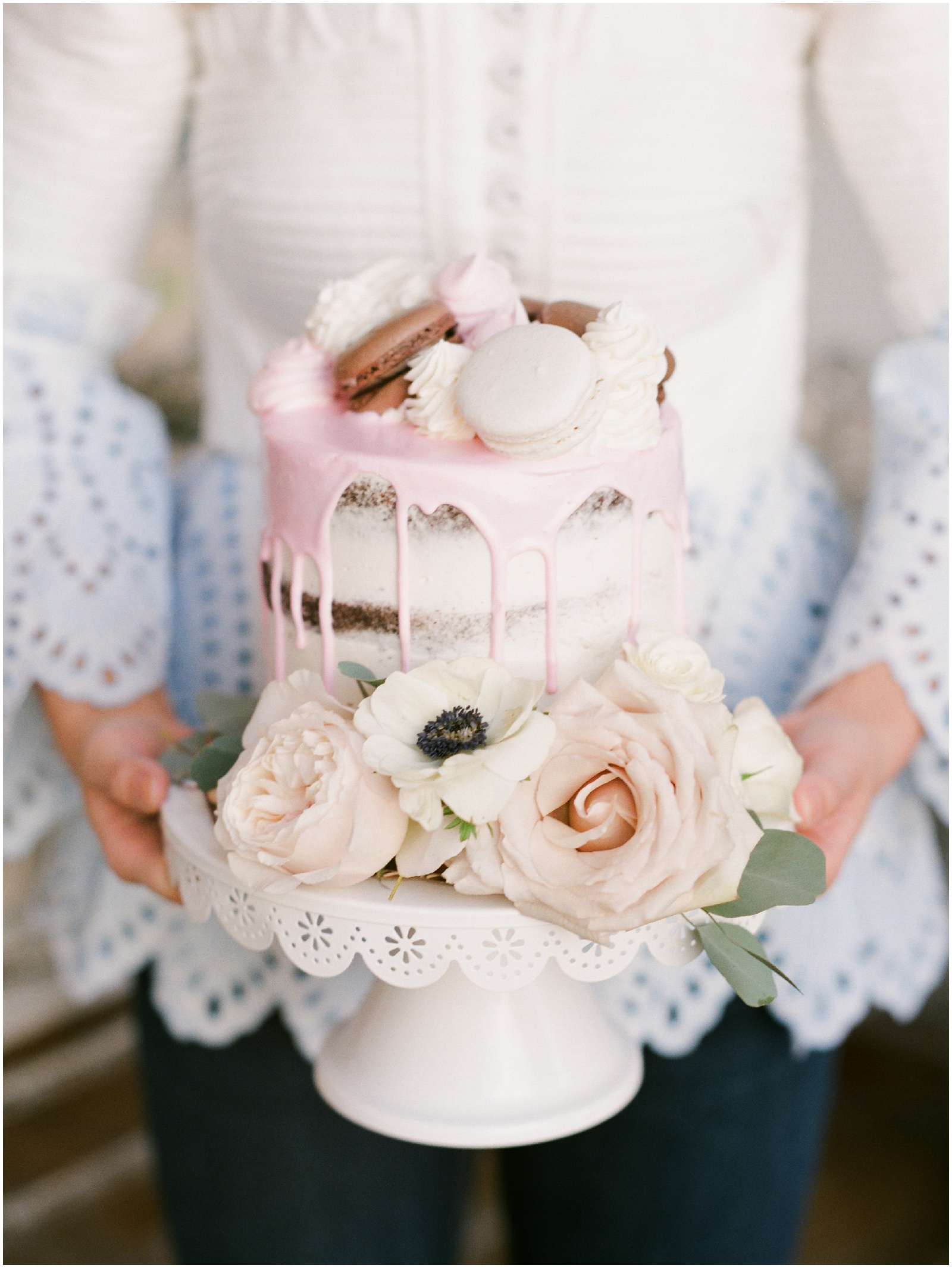 pink naked drip cake topped with macarons and lined with blush and white flowers