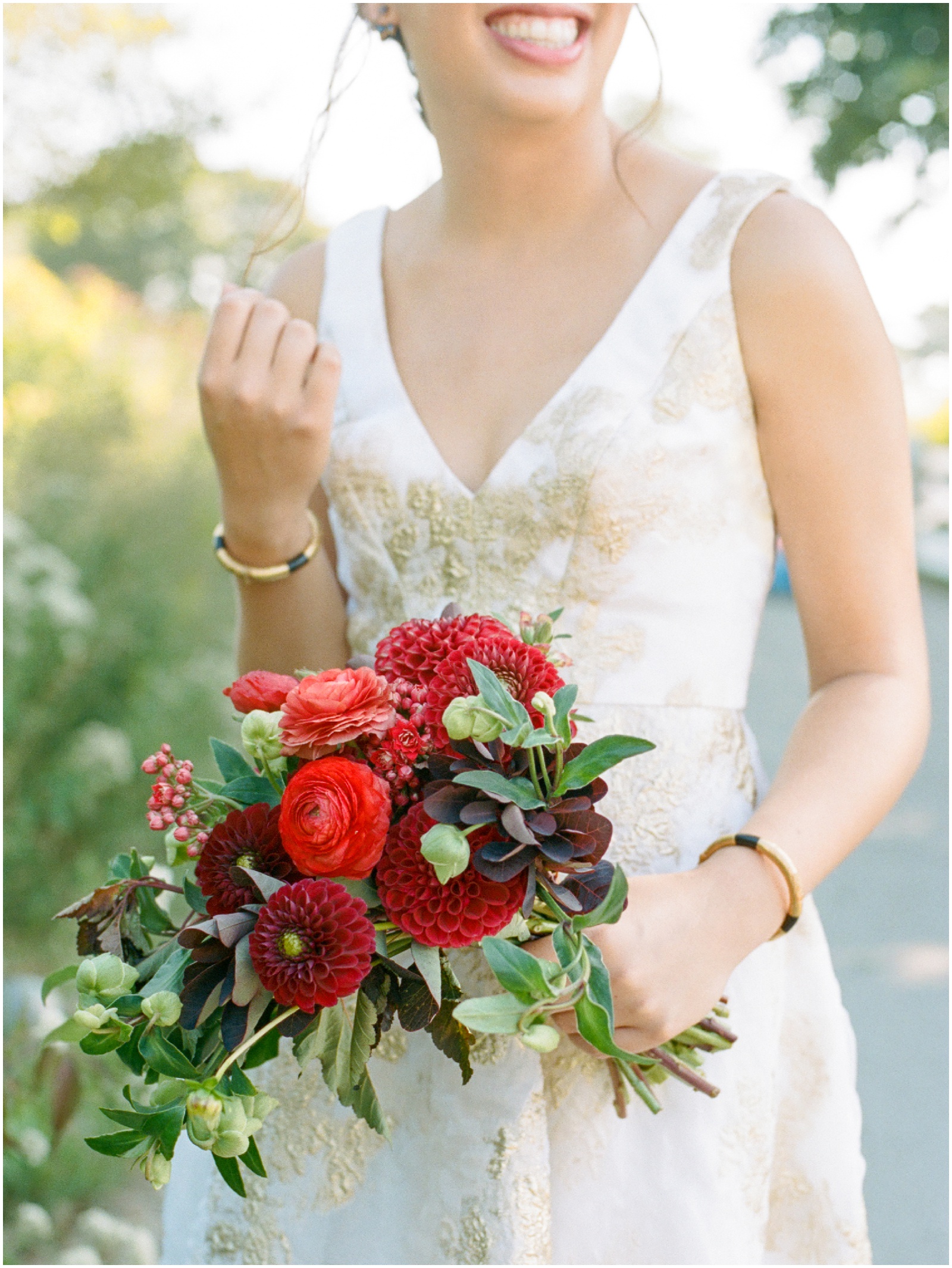 bride holding burgundy and green wedding bouquet