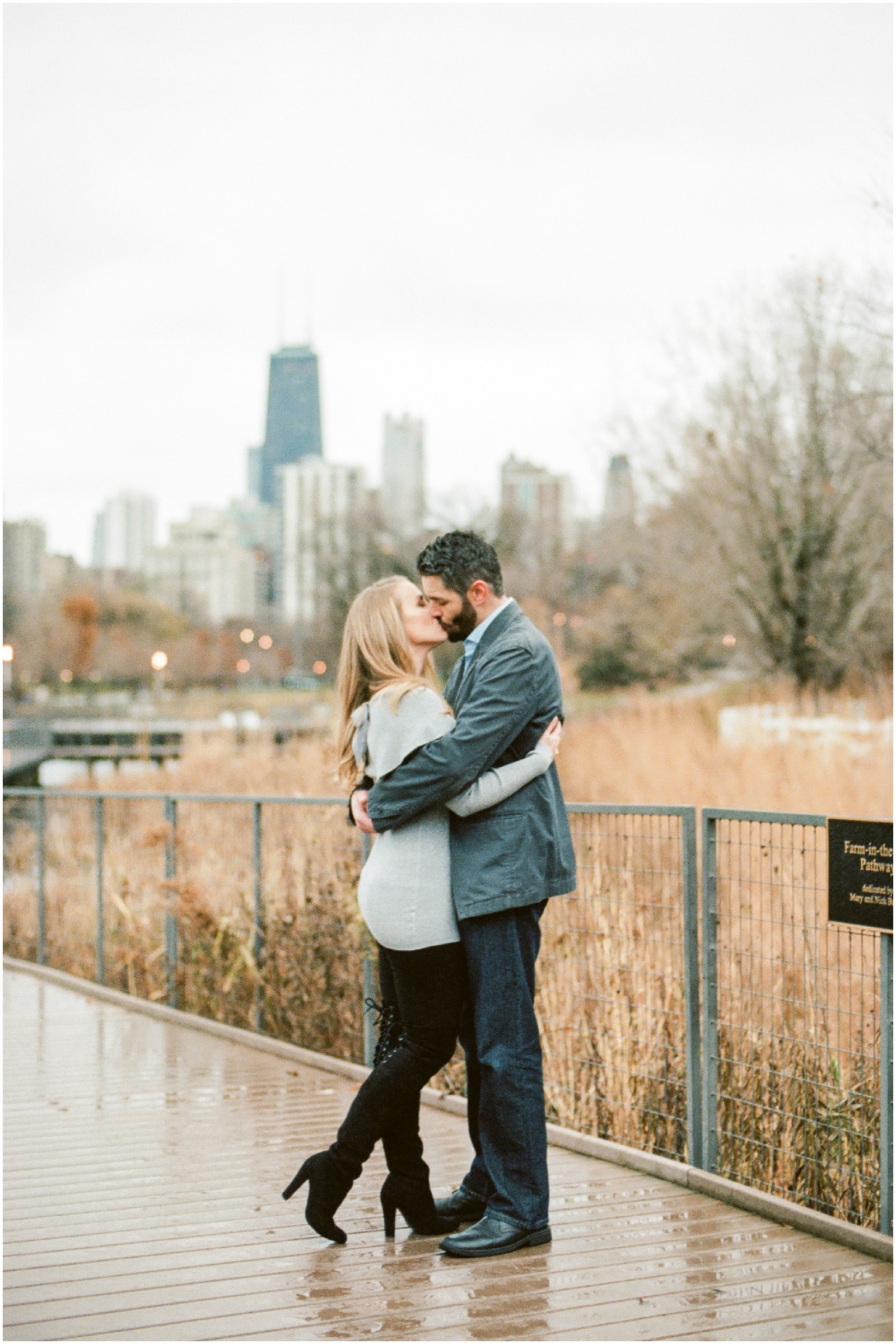 couple hugging on nature boardwalk overlooking city skyline for engagement photos