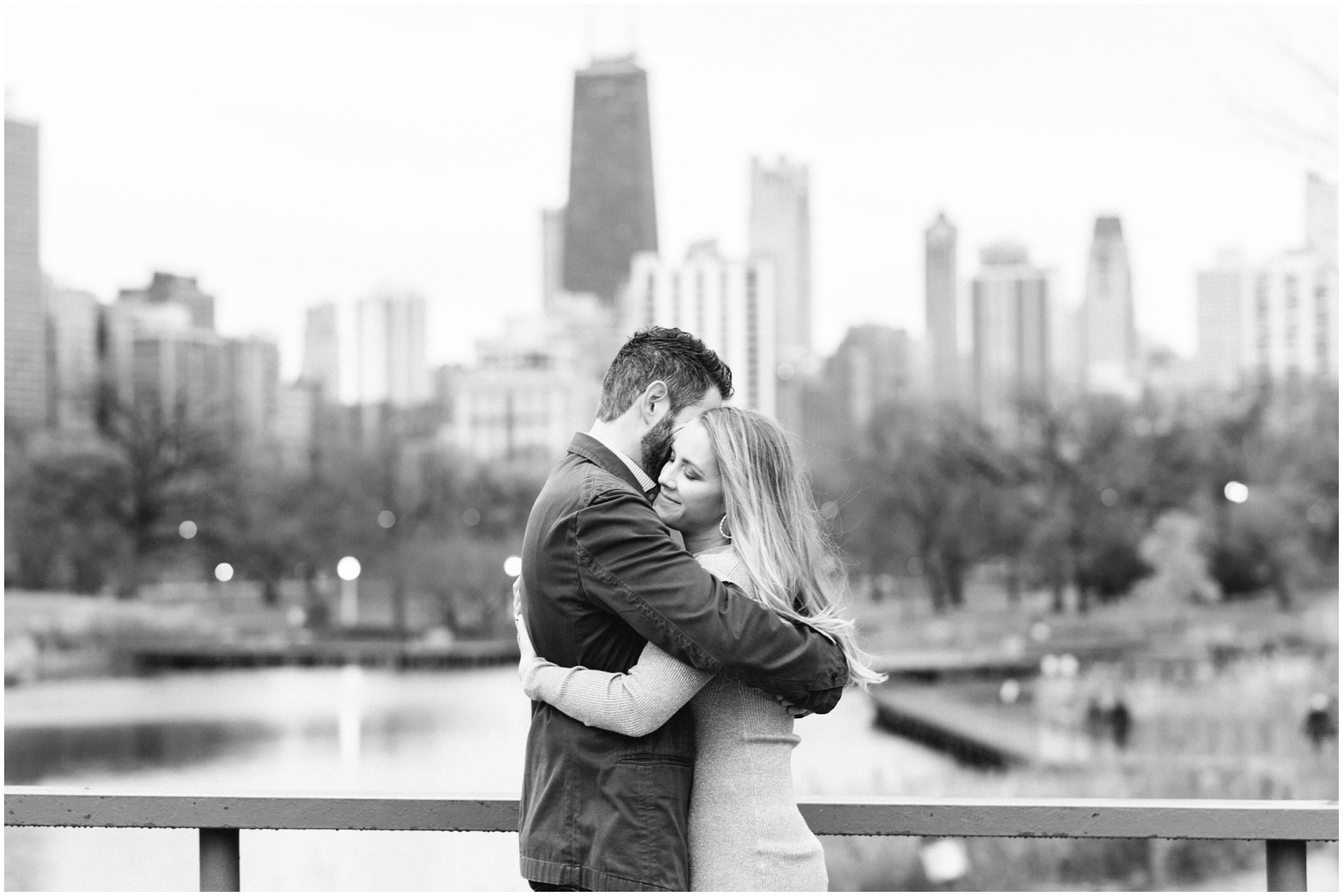 couple hugging on bridge with skyline in background