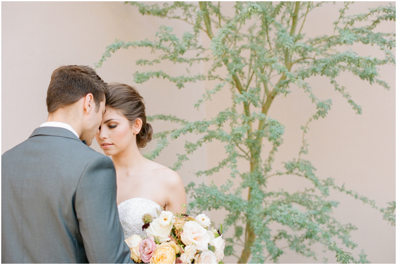 bride and groom in front of pink wall with cactus