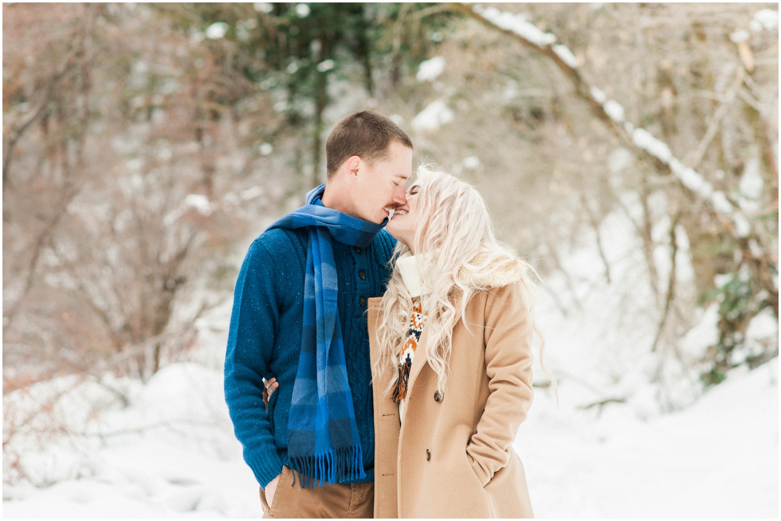 couple kissing in the snowy mountains during engagement session