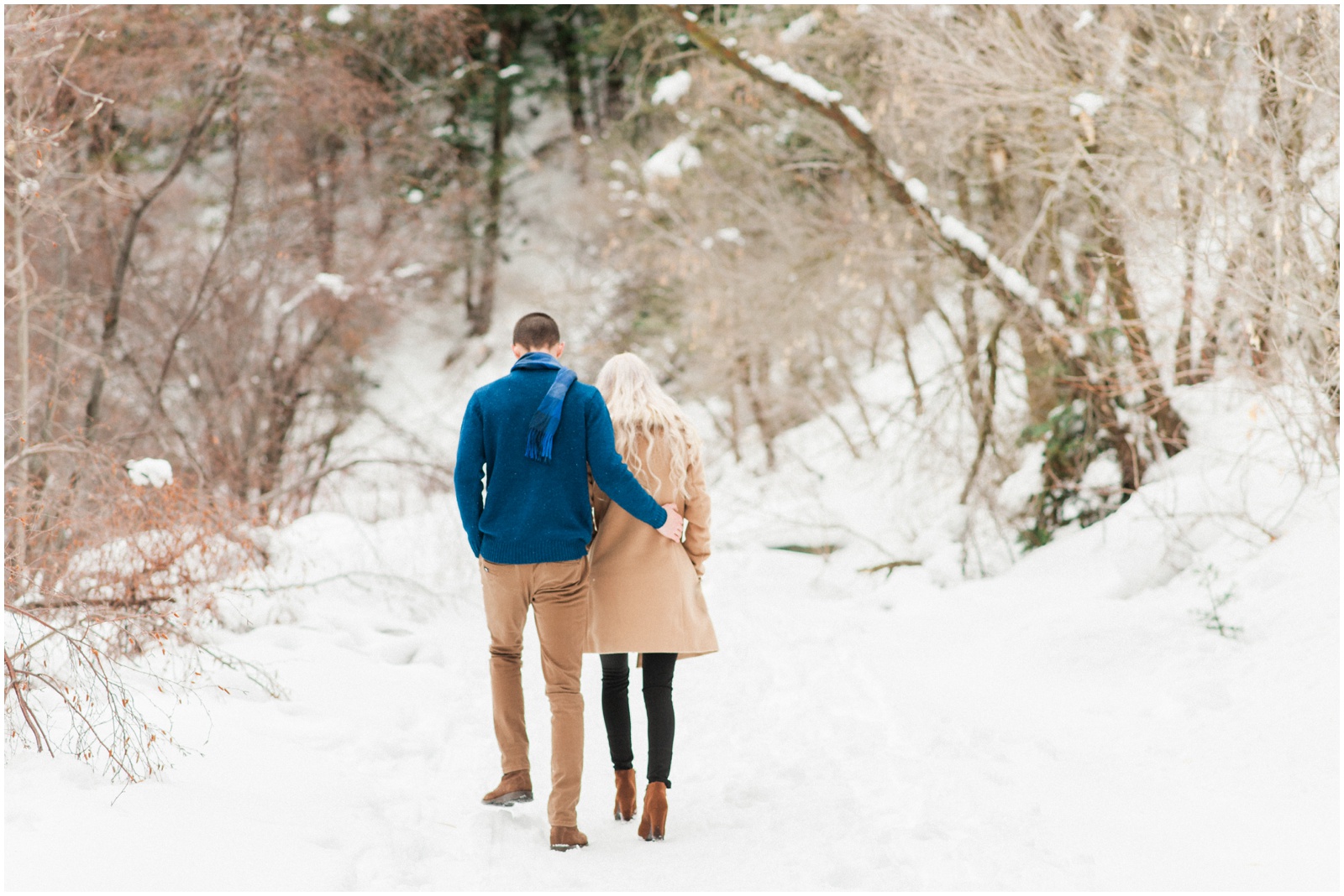 couple walking in the snow up a mountain trail during engagement sesison