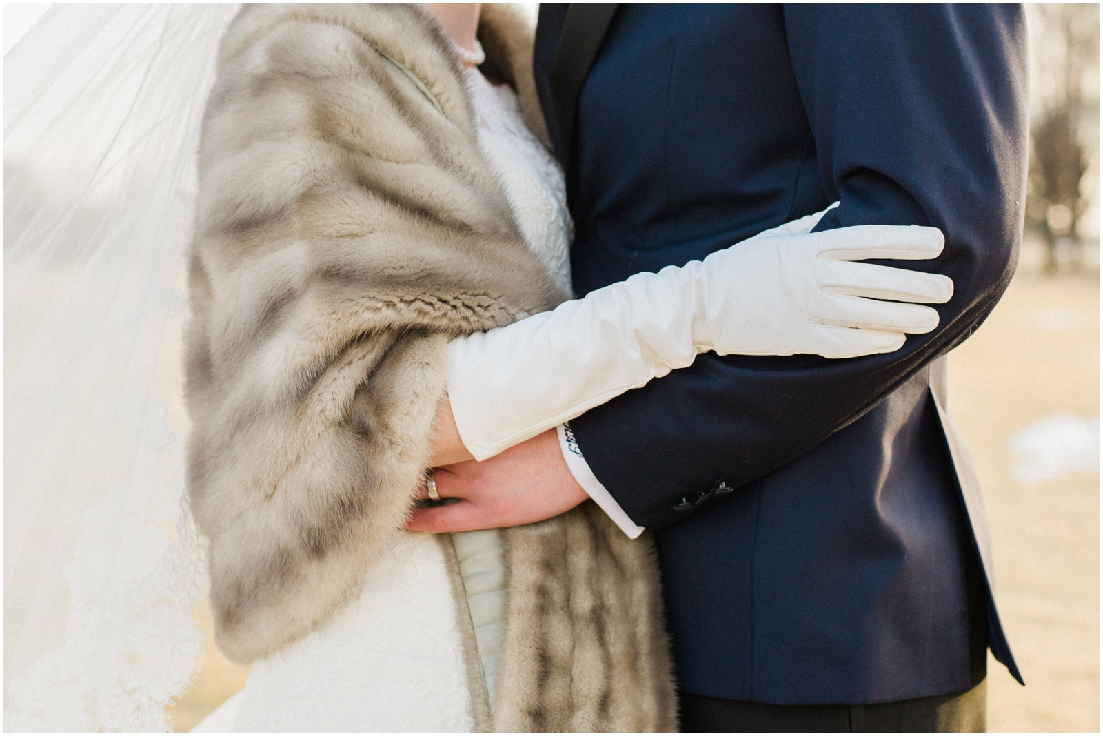bride wearing fur and white gloves hugging groom