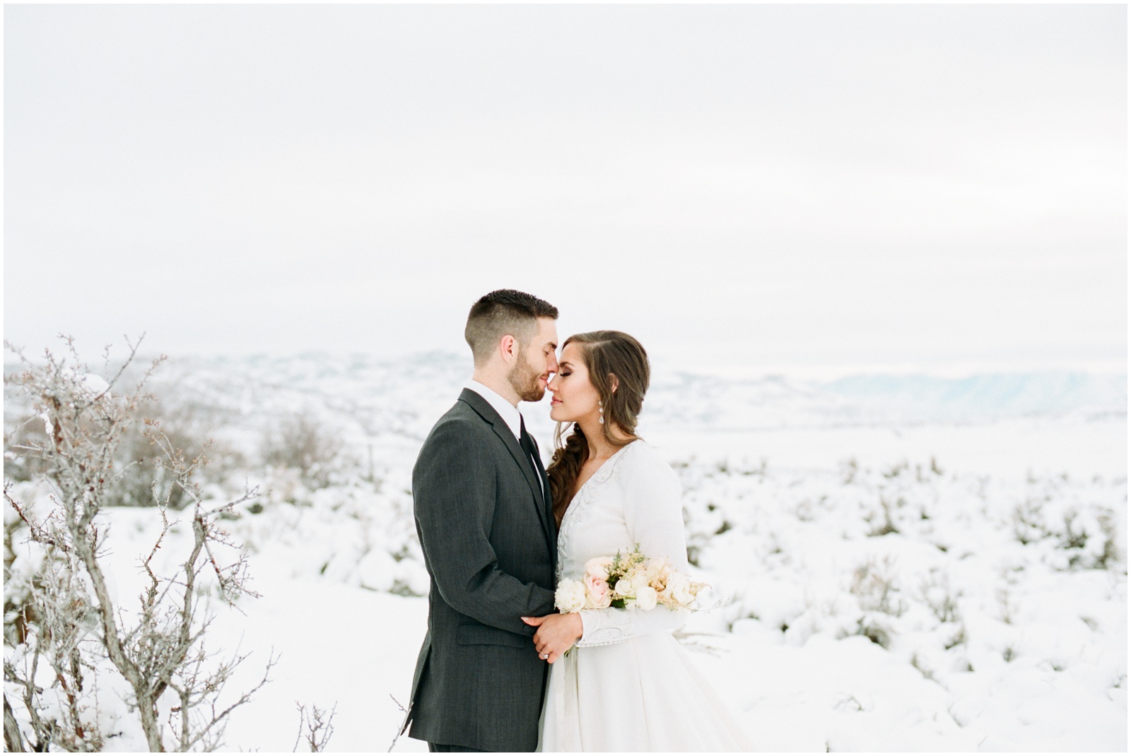 bride and groom standing in snowy mountains