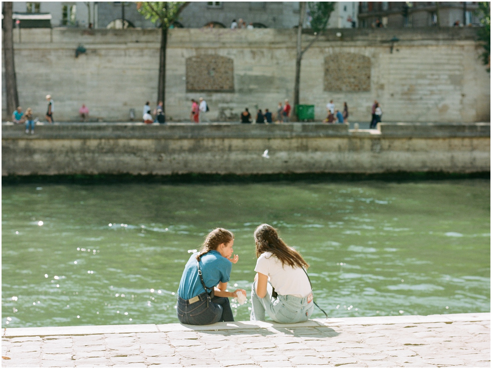 girls sitting beside the seine river in paris
